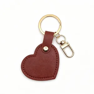 Minimalist brown heart leather keychain with gold metal hardware, perfect stylish bag pendant.
