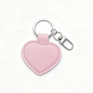 Close-up detail of smooth pink PU leather heart keychain with silver metal ring and clasp.