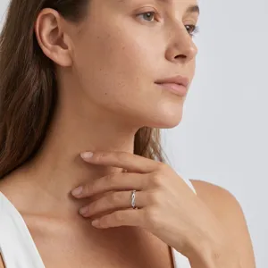 Gedetailleerde close-up van een minimalistische zilveren getwijnde ring bij een model.