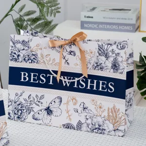 Detailansicht einer luxuriösen Papiertragetasche mit Blumenmuster und eleganter Goldschleife.