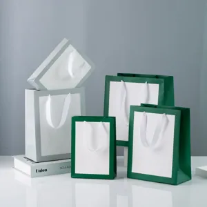 Detailed view of minimalist green and white paper gift bags with white ribbon handles for packing.