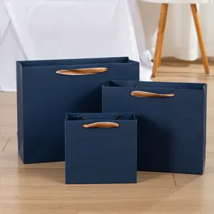 Detailansicht luxuriöser dunkelblauer Papiertragetaschen mit eleganten goldenen Bandgriffen.