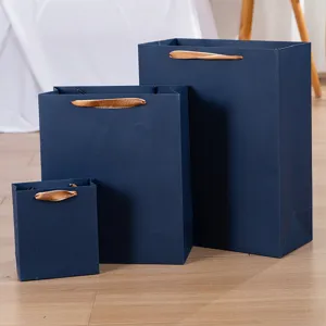 Dunkelblaue Papiertragetaschen Set mit goldenen Schleifengriffen, hochwertige Luxuspapiertüten.