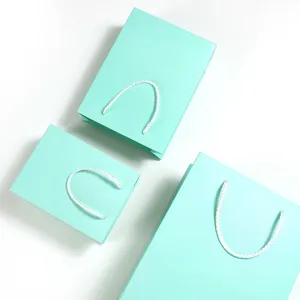 Set van tiffany blauwe papieren cadeauzakjes met witte handvatten voor feestdagen.