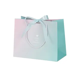 Gradient gift paper bag with ribbon bow, elegant shopping bag for holidays and parties.