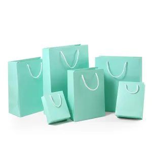 Turquoise papieren geschenkzakjes met witte handgrepen voor feestkleding en huwelijksverpakking