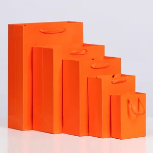 Set van oranje papieren geschenkzakken met lint handgrepen in verschillende maten voor verpakking