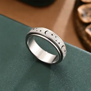 Close-up detail of the stainless steel spinner ring featuring frosted texture, stars and moon cutouts.