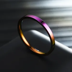 Close-up of a slim 2mm rainbow stainless steel ring showing vibrant metallic gradient shine.