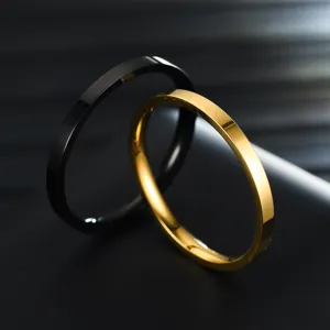 Close-up detail of minimalist stainless steel rings, smooth polished finish in black and gold.