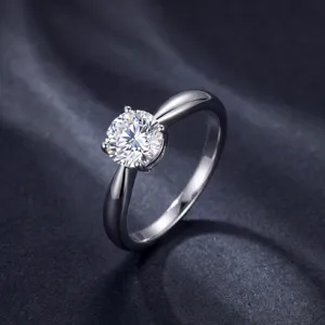 Gros plan d'une bague diamant ronde classique à quatre griffes, bracelet en argent lisses.