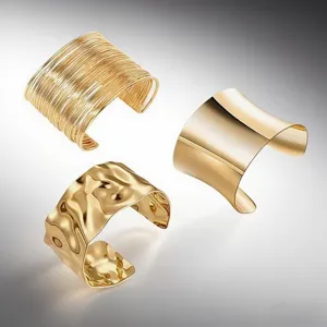 Detail view of trendy gold metal open cuff bracelets featuring unique textured and smooth styles.