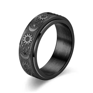 Detail view of a black titanium steel spinner ring featuring sun, moon, and star engravings.