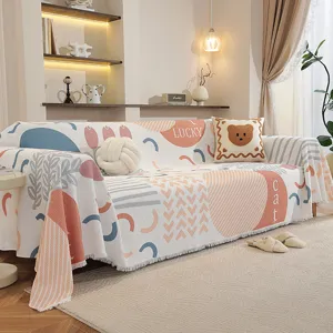 Détail d'un jeté de canapé de style scandinave avec des motifs géométriques et des pompons