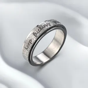 Detailed shot of stainless steel spinner ring with glitter finish and motivational engraved text.