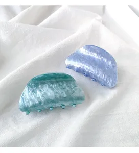Detailed close-up view of pearlescent acrylic hair claw clips in teal and lavender purple