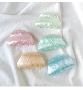 Five pastel colored acrylic shark claw clips displaying delicate marbleized textures