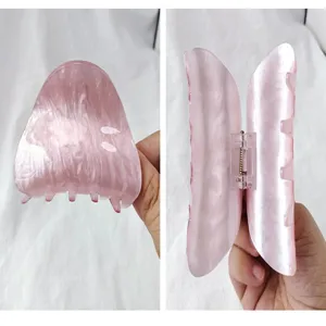 Detail of pink acrylic hair claw clip with marble pearl texture and sturdy grip.