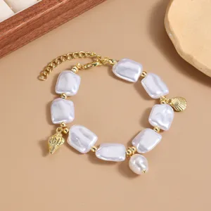 Elegante pulsera de perlas barrocas con dijes de conchas doradas y cuentas blancas