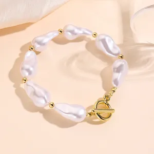 Vista de detalle macro de una pulsera de perlas barrocas con cuentas doradas y cierre