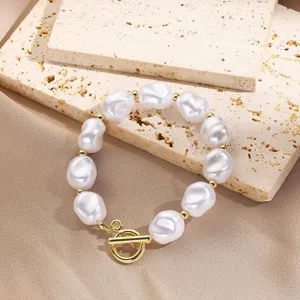 Primer plano detallado de una pulsera de perlas barrocas con elegante cierre en T dorado