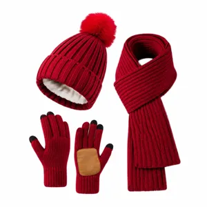 Detail view of a dark red winter set with knitted pom-pom hat, scarf, and warm gloves.