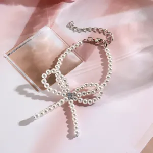 Detalle de una elegante pulsera de perlas en forma de lazo con un cristal central