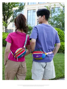 Outdoor lifestyle detail shot of a colorful patchwork waist bag worn by models on grass.