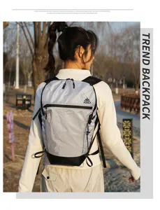 Detail view of the grid pattern outdoor backpack worn by a model in a park setting.