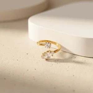 Close-up of dual stone crossover open ring with marquise zircon and delicate gold band.