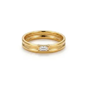 Close-up detail of double stacked gold ring with central baguette stone, elegant minimalist fine jewelry.