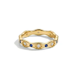 Gedetailleerde close-up van gouden golvende ring met witte bloemkristallen en blauwe stenen.