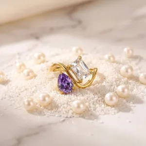 Closeup view of a gold-plated titanium steel ring featuring a purple and clear gemstone design.