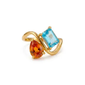 Close-up detail of the double-stone gold ring featuring orange and blue gemstone crystals.