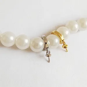 Close up detail of DIY pearl necklace connector, golden and silver jewelry bail findings.