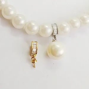 Close-up detail of pearl necklace bail clasp, shiny zircon setting and jewelry accessory.