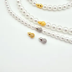 Detail view of pearl necklace clasps, showing gold and silver gourd screw clasps with faux pearls.