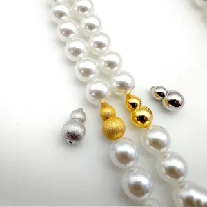 Close-up detail of pearl necklace clasp, metal gourd screw clasp accessory, smooth finish.