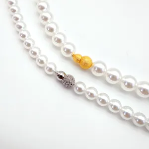 Pearl necklace clasp detail showing brushed gold gourd and silver pave screw clasp elements.