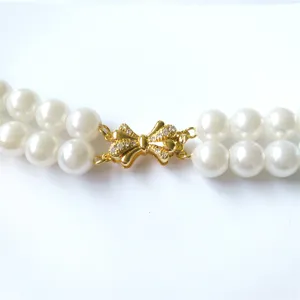 Close-up detail of double strand pearl necklace clasp, gold plated bow connector with crystals.