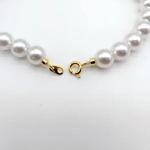 Close-up detail of white pearl necklace clasp with gold-plated spring ring and connector.