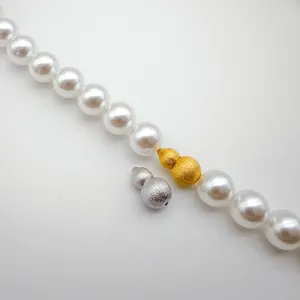 Detailed view of pearl necklace clasp, brushed gold and silver gourd screw clasps.