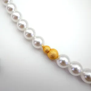 Stunning close-up detail shot of a pearl necklace featuring an exquisite frosted gold gourd clasp.