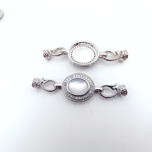 Close-up of silver DIY jewelry clasp with mother-of-pearl inlay and twisted connection.