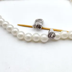 Detail view of silver metal DIY jewelry clasp connector and pearl accessories for crafting.