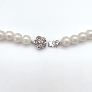 Close-up detail shot of the elegant camellia pearl necklace insert clasp accessory.