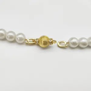 Close-up detail of gold plated lantern ball jewelry clasp connector with pearl beads.
