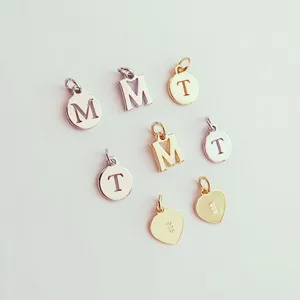 Close-up details of DIY metal letter charms and heart pendants, polished finish for jewelry.