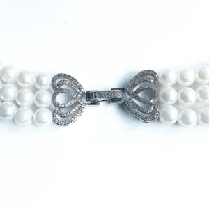 Detailed view of multi-strand faux pearl necklace clasp with sparkling rhinestone heart design.