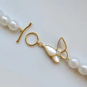 Closeup detail of gold plated butterfly OT toggle clasp with pearls and mother of pearl charm.
